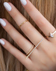 A dainty 14k yellow gold two finger ring, with a long bar set with white diamonds, that covers both fingers.