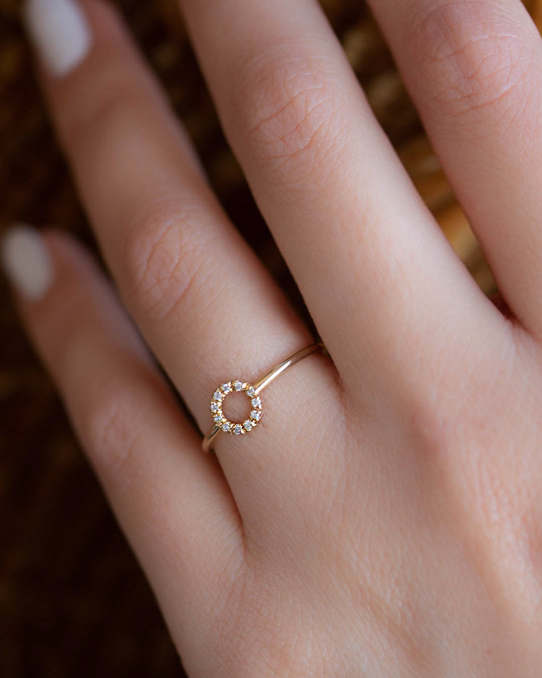 A dainty 14k yellow gold ring with a circle on top, set with brilliant cut white diamonds.