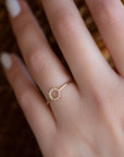 A dainty 14k yellow gold ring with a circle on top, set with brilliant cut white diamonds.