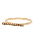 A dainty 14k yellow gold ring, with a horizontal bar on top, set with ten tiny white diamonds.