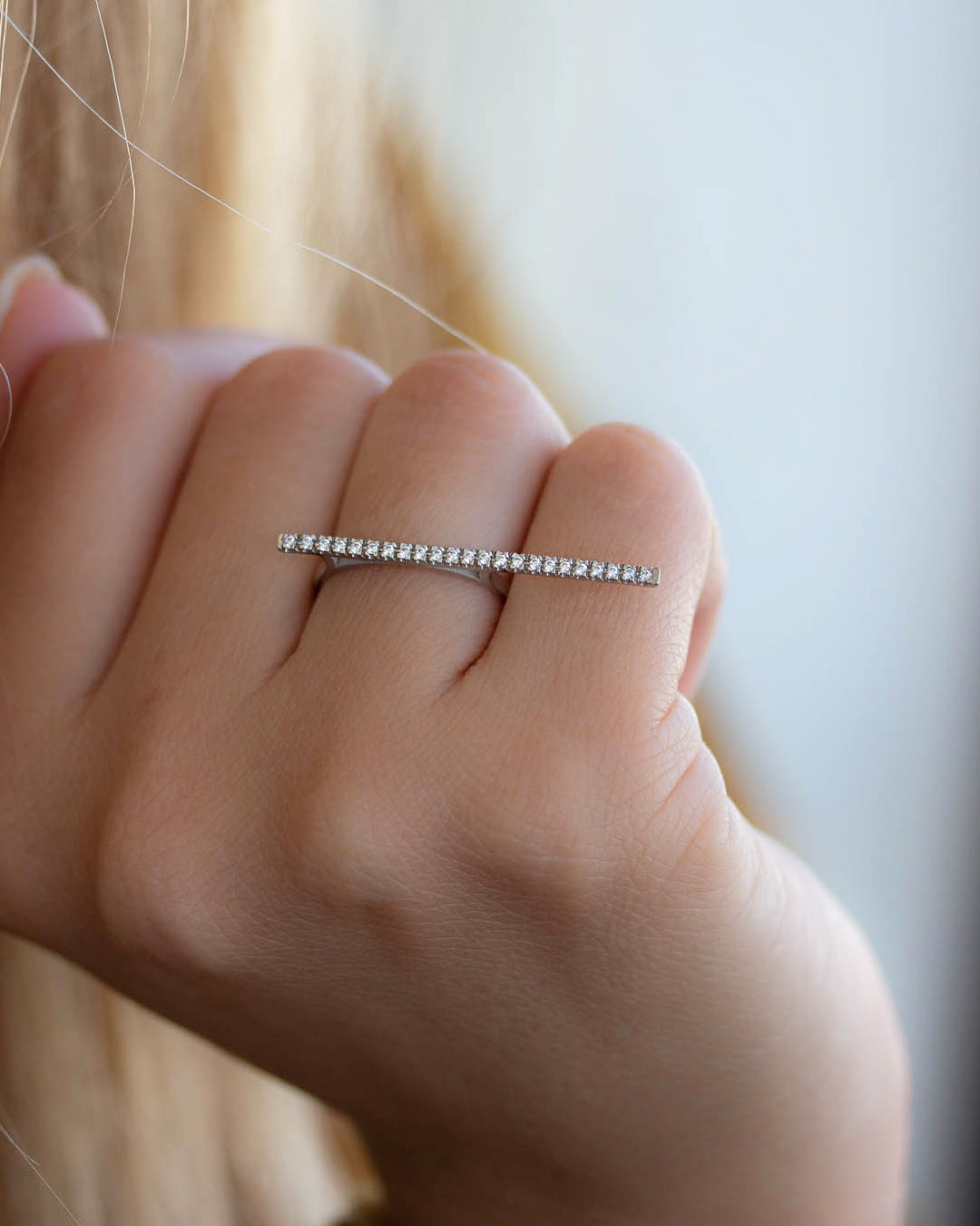 A dainty 14k white gold two finger ring, with a long bar set with white diamonds, that covers both fingers.