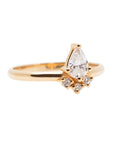 A 14k yellow gold engagement ring, set with a center pear cut white diamond and and halo of three small white diamonds.