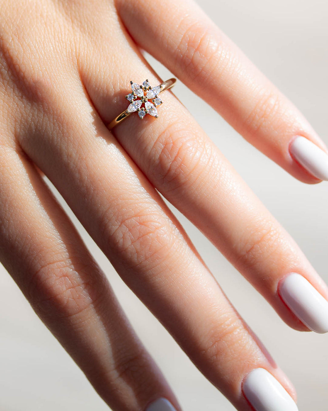 A delicate 14k yellow gold engagement ring set with four marquise cut white diamonds, and four brilliant cut white diamonds, in a shape of a snowflake.