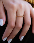 A dainty 14k yellow gold ring, with a horizontal bar on top, set with nine tiny white diamonds.