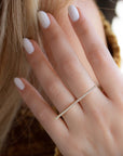 A dainty 14k yellow gold two finger ring, with a long bar set with white diamonds, that covers both fingers.