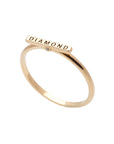 A delicate 14k yellow gold ring, engraved with DIAMOND on top and set with two tiny white diamonds.