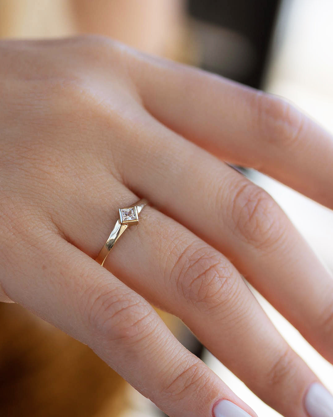A delicate 14k yellow gold engagement ring set with a center 0.25 carat princess cut white diamond. 