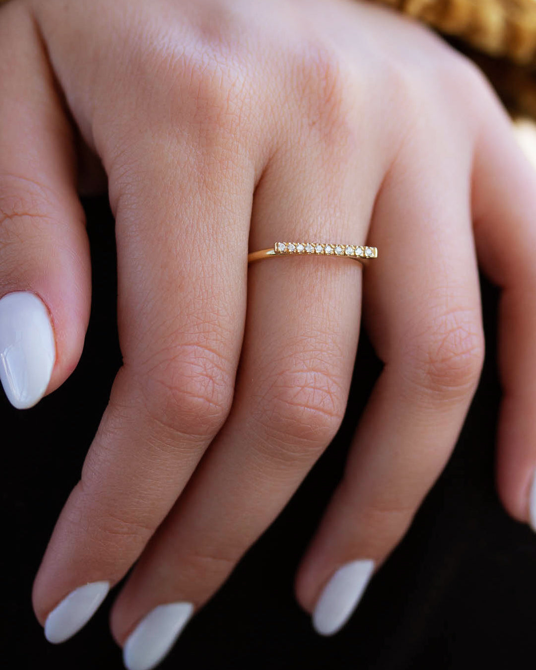 A dainty 14k yellow gold ring, with a horizontal bar on top, set with nine tiny white diamonds. 