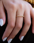 A dainty 14k yellow gold ring, with a horizontal bar on top, set with nine tiny white diamonds. 