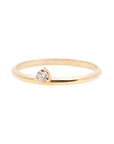 A dainty 14k yellow gold ring, set with one tiny, brilliant cut white diamond.